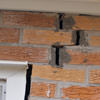 A brick wall displaying stair-step cracks and messy tuckpointing on a Sparks home