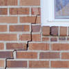 long jagged cracks starting at the corner of a window along a brick wall on a Tahoe City home