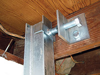 Securing the i-beam system to the top of the floor joist in a foundation wall repair in Fernley.