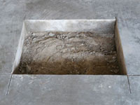 Creating the hole in the garage slab floor during the wall anchor installation in Stateline.